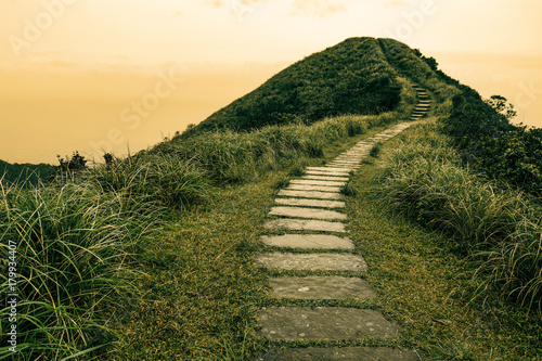 Fotografie, Obraz Fairy tale landscape and stepping stone path over a hill on the horizon at the C