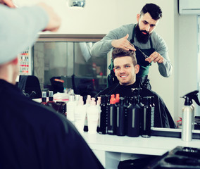 male hairdresser doing haircut for male client at hair salon