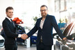 Two men handshaking in car dealership