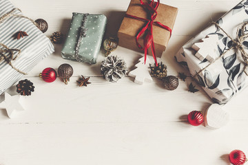 Wall Mural - merry christmas concept, flat lay. presents with ornaments pine cones anise on rustic white wooden background top view, space for text. seasonal greetings card. happy holidays.