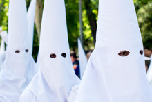 Penitents (Nazarenes) Wearing White Masks In A Holy Week Procession In Seville (Spain)