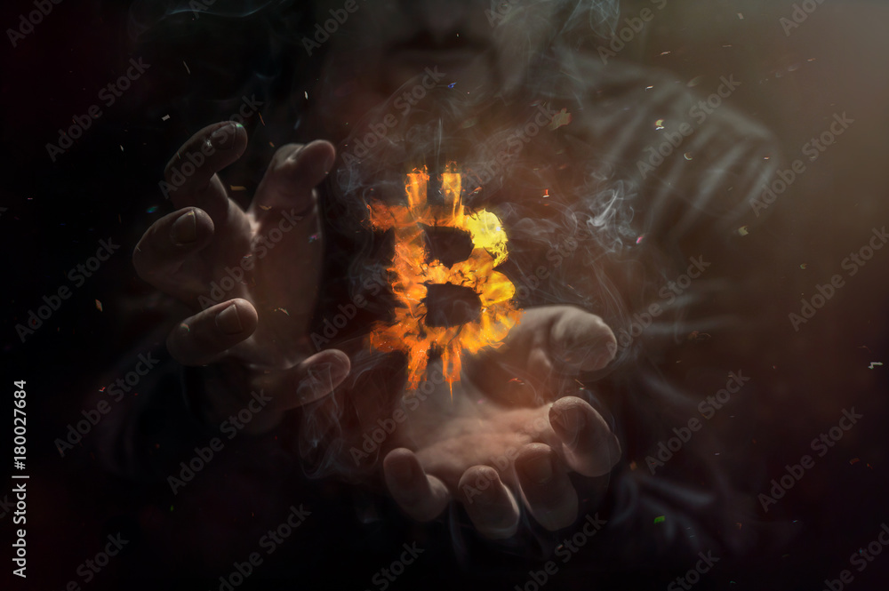 Burning symbol of bitcoin with man in the background. Conception of risk management in money trading at currency market