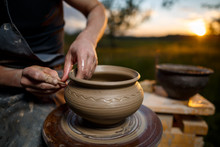 Clay Potter Creating On The Pottery Wheel. Sculptor From Fresh Wet Clay On Pottery Wheel. Selected Focus. Hands Of Young Potter Was Produced On Range Of Pot In Open Air
