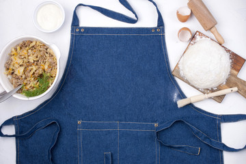 products for cooking pie with meat, on a white background and blue denim apron