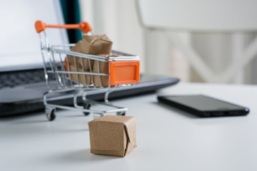 Online shopping concept. Shopping cart, small boxes, laptop and smartphone on the desk