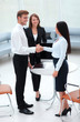 © ASDF - business partners shaking hands while standing in the lobby of the office.