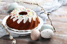 Bundt Cake With Sprinkles And Easter Eggs On Wooden Table