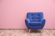 Blue armchair near color wall