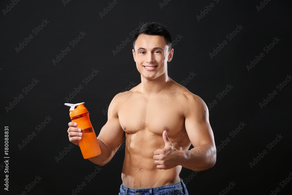 Sporty young man with protein shake on black background