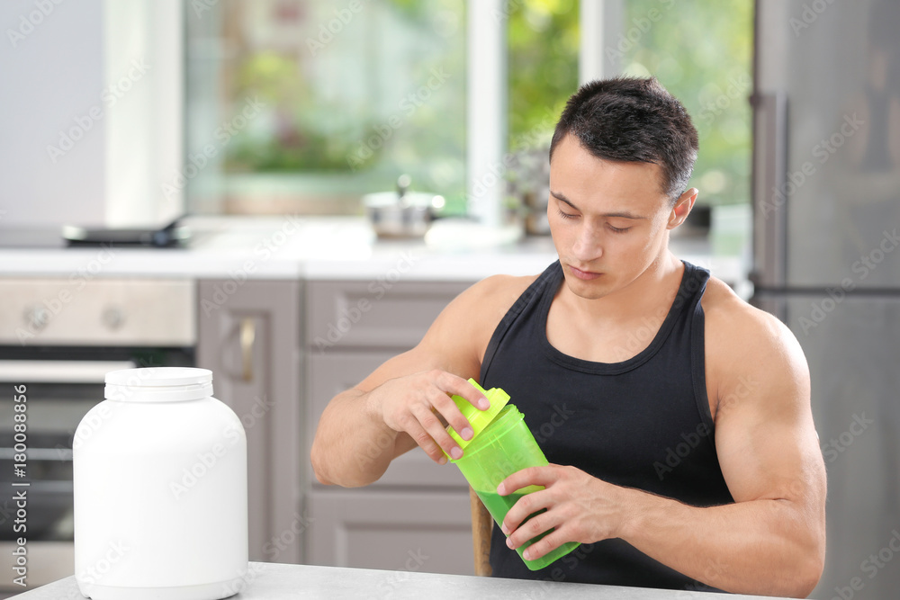 Sporty young man with protein shake in kitchen