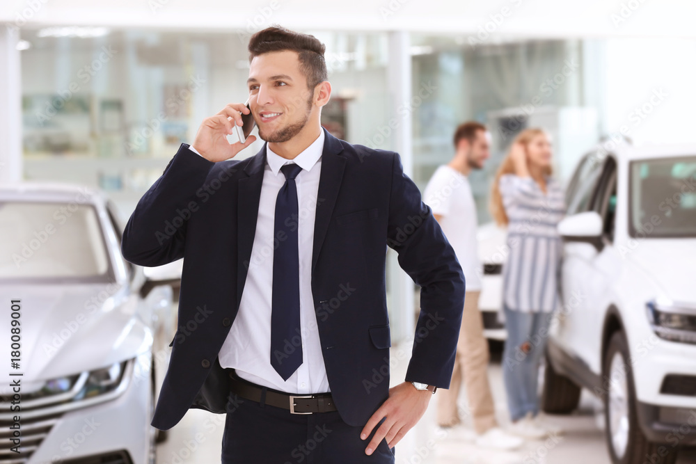Car salesman talking on phone in dealership