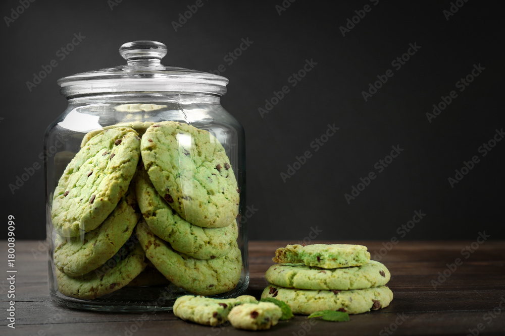 Jar with mint chocolate chip cookies on wooden table