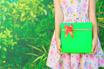 Girl holds a gift or a surprise in hand flower garden background, Green style