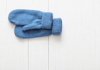 blue mittens on white wooden background