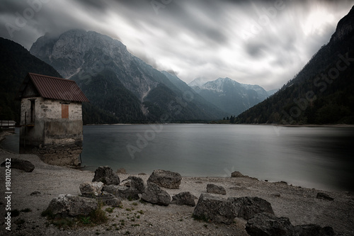Plakat Mały kamienia dom na brzeg halny jezioro w chmurnej pogodzie, dolomity, Włochy