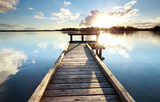 Fototapeta Pomosty - gold sunshine over wooden pier on big lake
