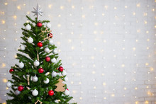 Decorated Christmas Tree Over White Brick Wall With Lights