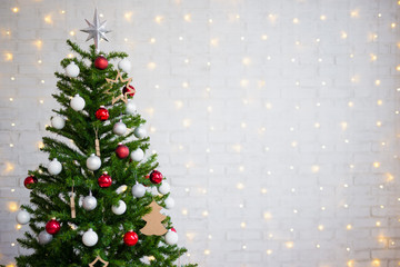 decorated christmas tree over white brick wall with lights