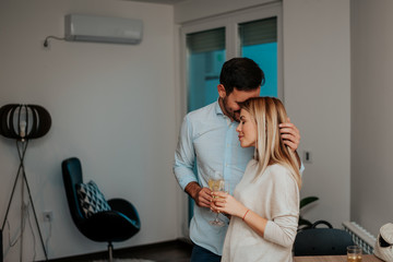 Wall Mural - Young couple in living room hugging.