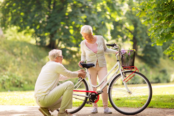 happy senior couple with bicycle at summer park