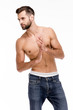 © MARIIA - Gorgeous and handsome. Handsome shirtless young man in jeans looking away while standing against white background