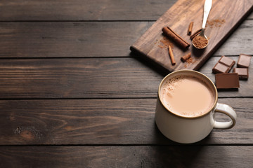 Wall Mural - Mug with delicious cocoa drink on wooden background