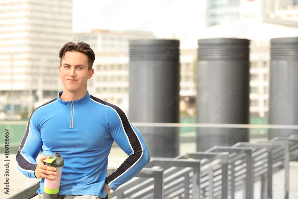 Sporty young man with protein shake, outdoors