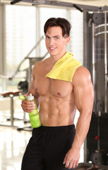 Poster - Muscular young man with bottle of water in gym