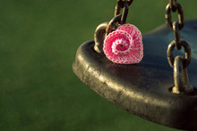 Pink Crocheted Spiral Heart  Lies On Swing On Green Background. Theme Valentine's Day