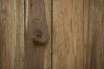 a close-up of a wooden surface with vertical planks, featuring a knot in the center of the wood.