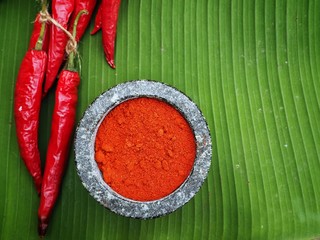 Canvas Print - Chili powder with mortar on banana leaves background