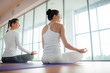 © pressmaster - Two girls keeping balance in pose of lotus in front of window in gym