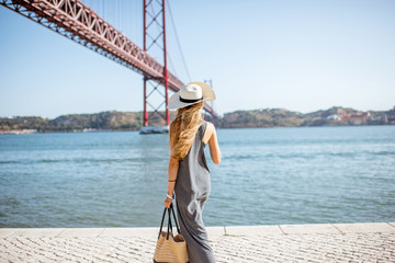 lifestyle portrait of a woman walking on the riverside with beautiful iron bridge on the background 