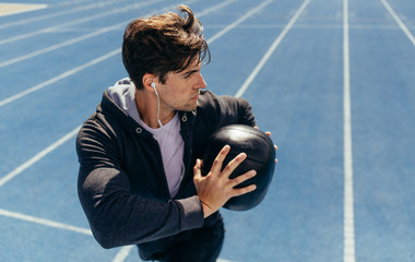 Wall Mural - athlete training with a medicine ball on running track