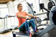 © NDABCREATIVITY - Young blonde woman working on rowing machine