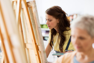 Wall Mural - student girl with easel painting at art school