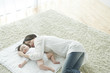 © amanaimages - Mother with baby lying on carpet