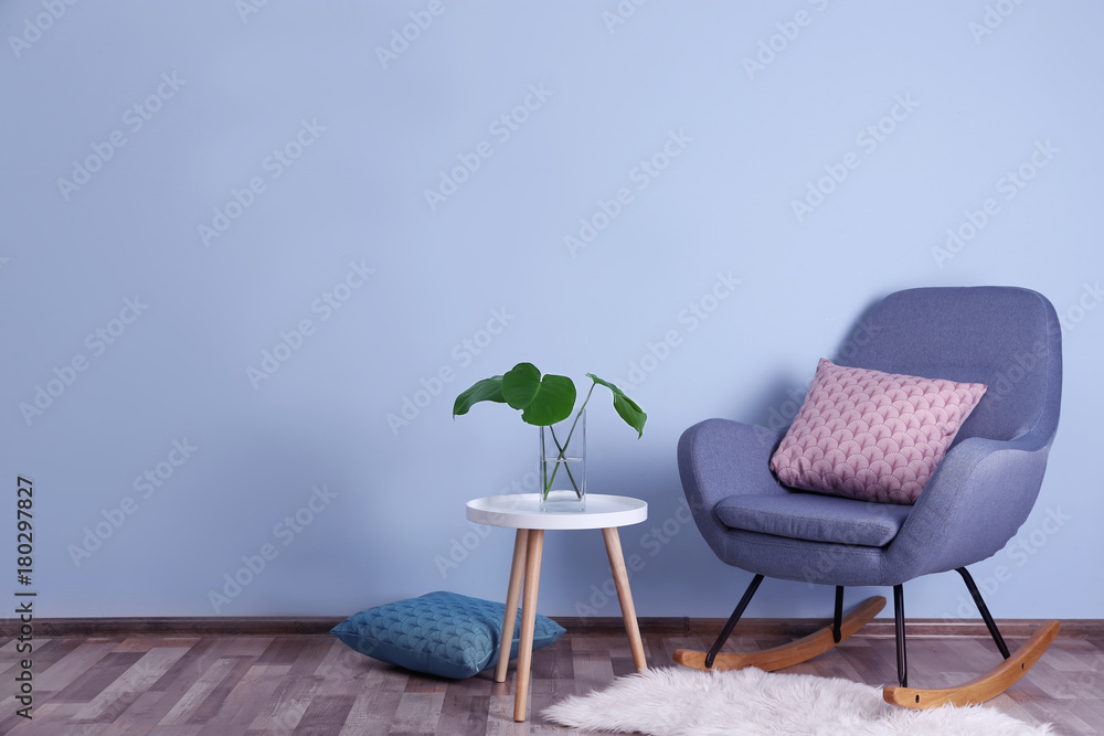 Stylish room interior with monstera leaves in vase on table