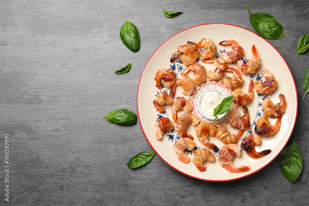 Plate with shrimps wrapped in bacon and sauce on table