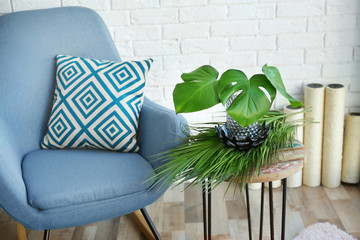 Stylish room interior with tropical leaves on table