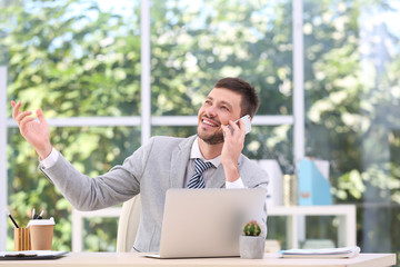 Sticker - Handsome businessman talking on mobile phone while working in office