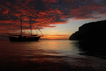 Sailing boat in the sea with red sky sunset