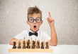 © Ermolaev Alexandr - smart boy sits at the chessboard and shows finger up. Idea concept
