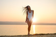 © arthurhidden - Young woman in strings swimsuit stands on the beach in sunrise