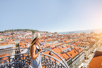 Wall Mural - Young woman tourist enjoying beautiful cityscape top view on the old town during the sunny day in Lisbon city, Portugal