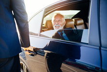 Senior business man sitting in his limousine. Business concept. Back light.