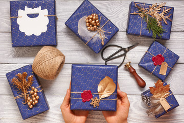 Sticker - Woman wrapping christmas presents over wooden background