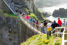 Thousands Of Tourists Visiting Carrick-a-Rede Rope Bridge In County Antrim Of Northern Ireland, Hanging 30m Above Rocks And Spanning 20m, Linking Mainland With The Tiny Island Of Carrickarede