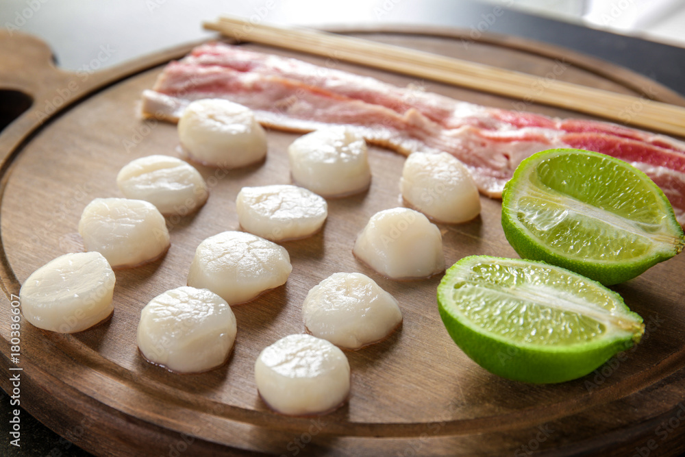 Wooden board with raw bacon and scallops, closeup