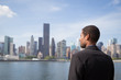 Side view of young African American business man looking at NYC skyline across the river, contemplating, contemplating